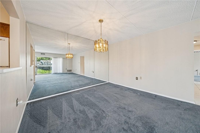 unfurnished dining area featuring a chandelier, carpet flooring, a textured ceiling, and baseboards