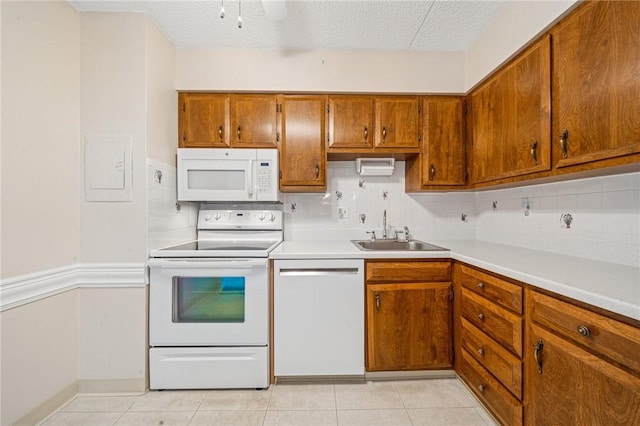 kitchen with white appliances, a sink, decorative backsplash, brown cabinetry, and light tile patterned floors