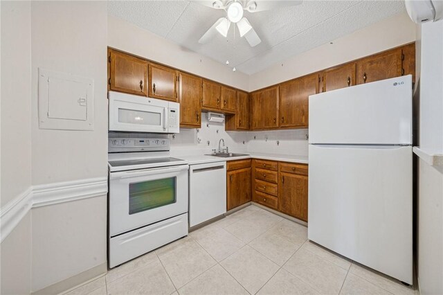 kitchen featuring white appliances, a sink, light countertops, a textured ceiling, and brown cabinetry