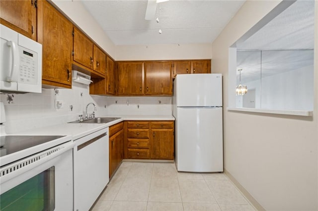 kitchen with white appliances, a sink, brown cabinetry, and decorative backsplash