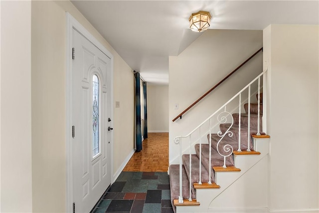 foyer featuring stairs and baseboards