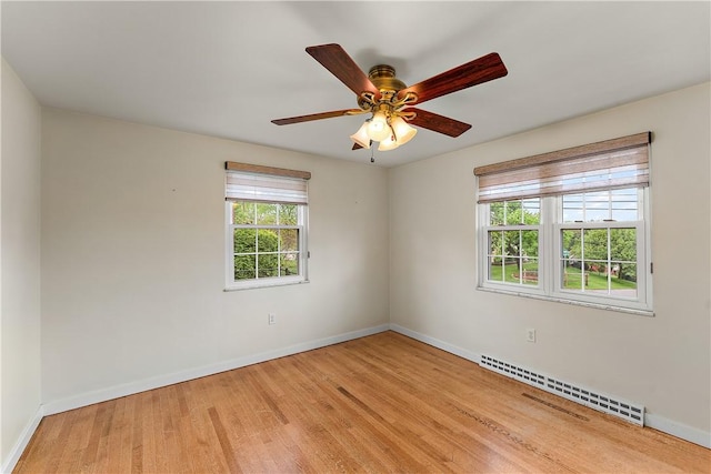 unfurnished room with baseboard heating, wood finished floors, baseboards, and a ceiling fan