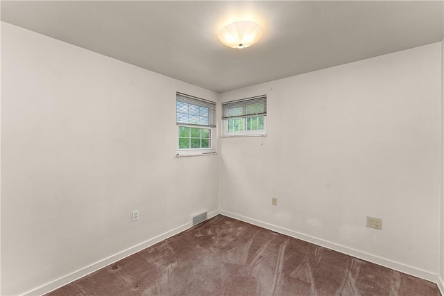 unfurnished room featuring dark colored carpet and baseboards