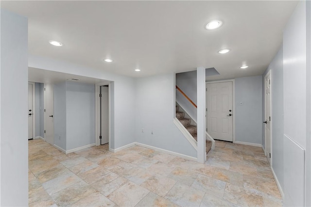 finished below grade area featuring baseboards, recessed lighting, stairs, and light stone finish floors