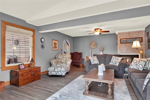 living area featuring wood finished floors, baseboards, a ceiling fan, and an accent wall