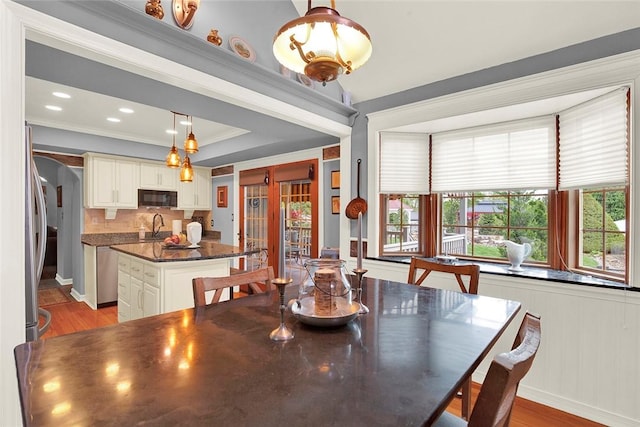 dining area with wood finished floors, crown molding, and baseboards