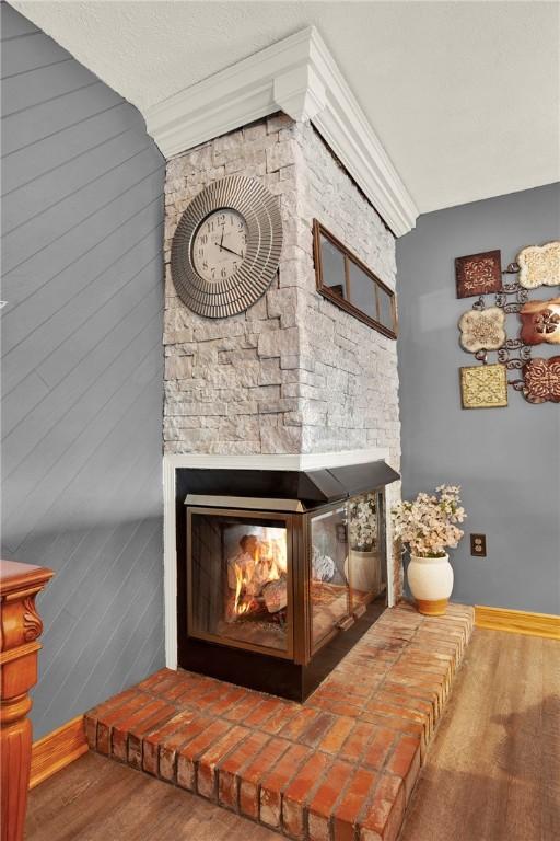 detailed view of baseboards, wood finished floors, and a multi sided fireplace