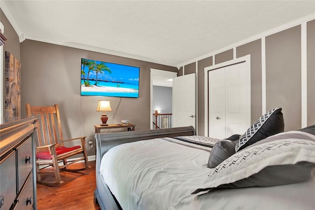 bedroom featuring ornamental molding, wood finished floors, a closet, and baseboards