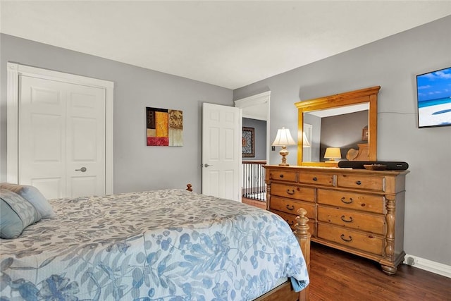 bedroom with dark wood-style floors, baseboards, and a closet