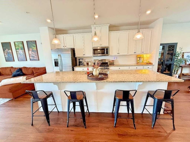 kitchen with appliances with stainless steel finishes, a breakfast bar area, white cabinetry, a large island, and recessed lighting