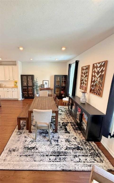 dining space featuring a textured ceiling, wood finished floors, recessed lighting, and baseboards