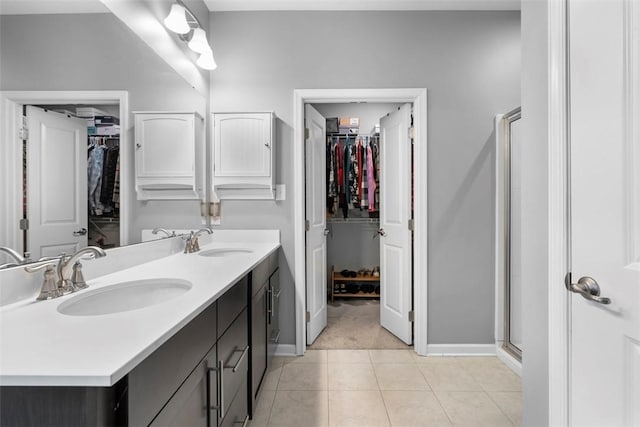 bathroom featuring baseboards, a stall shower, double vanity, and a walk in closet