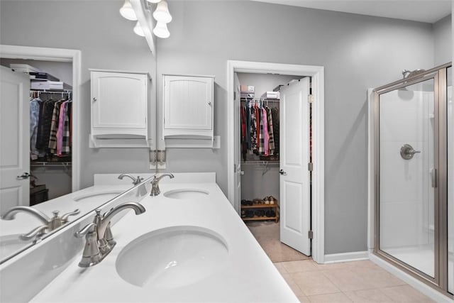 full bathroom with tile patterned floors, a stall shower, double vanity, and a spacious closet