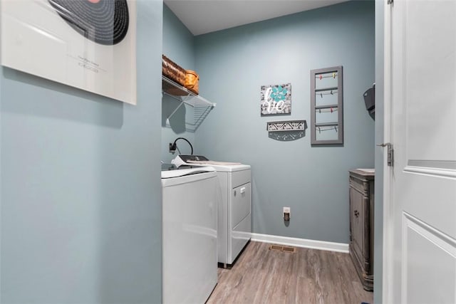 laundry room with washer and dryer, light wood-style floors, and baseboards