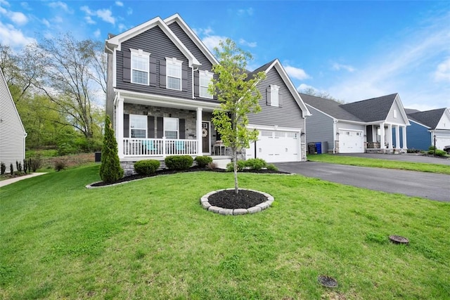 traditional home featuring covered porch, asphalt driveway, a front yard, and a garage