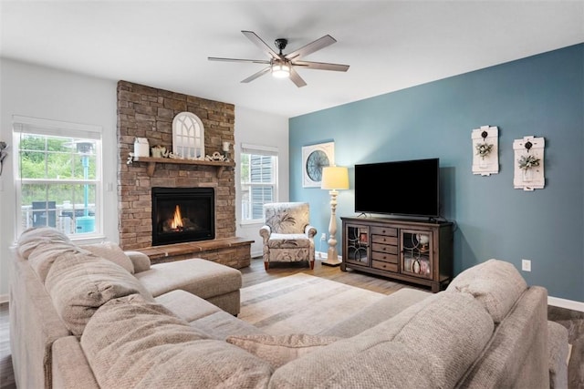 living area with wood finished floors, ceiling fan, baseboards, and a fireplace