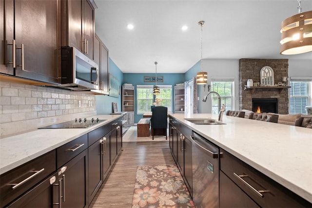 kitchen featuring appliances with stainless steel finishes, a sink, dark brown cabinetry, light wood-type flooring, and backsplash