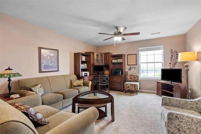 living area featuring light colored carpet, ceiling fan, and baseboards