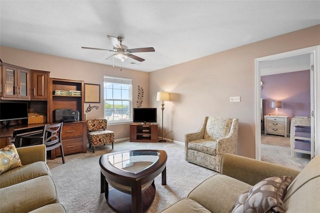 living room featuring light carpet, a ceiling fan, an office area, and baseboards