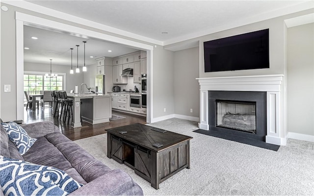 living room featuring a fireplace with flush hearth, a chandelier, baseboards, and recessed lighting