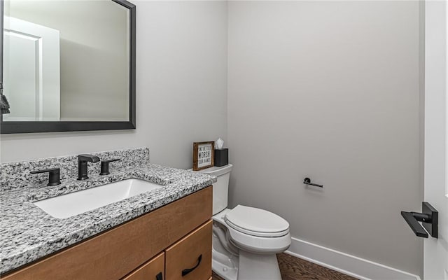 bathroom with toilet, vanity, and baseboards