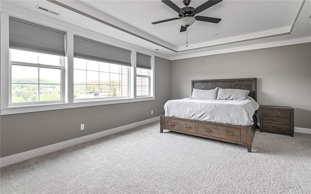 carpeted bedroom featuring a tray ceiling, baseboards, and a ceiling fan