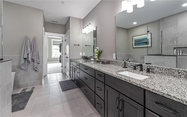 bathroom featuring double vanity, a walk in shower, and tile patterned floors