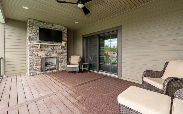 deck featuring an outdoor fireplace and a ceiling fan