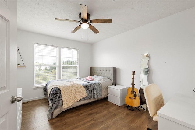 bedroom featuring dark wood-style flooring, a ceiling fan, and baseboards