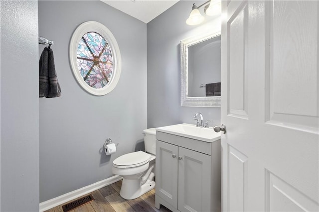 bathroom with wood finished floors, vanity, toilet, and baseboards