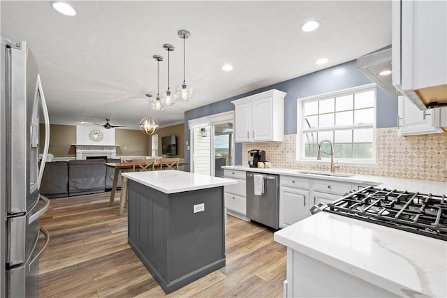 kitchen featuring stainless steel appliances, a sink, a kitchen island, open floor plan, and a fireplace