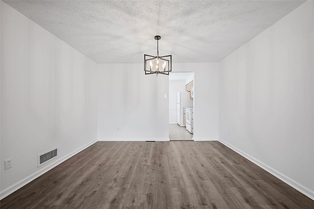 unfurnished dining area featuring a chandelier, dark wood finished floors, a textured ceiling, and baseboards
