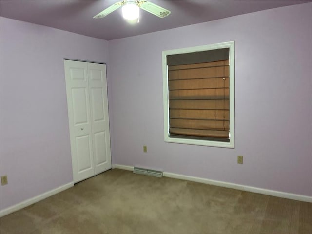carpeted empty room with a ceiling fan and baseboards