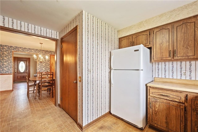 639 Scenery Dr, Elizabeth Twp/Boro, PA 15037 - kitchen featuring freestanding refrigerator, wallpapered walls, a chandelier, brown cabinets, and light countertops