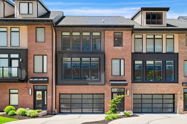 view of property featuring an attached garage, driveway, and brick siding