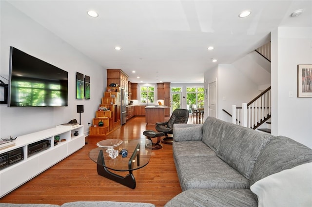 living room featuring recessed lighting, light wood-style floors, and stairway