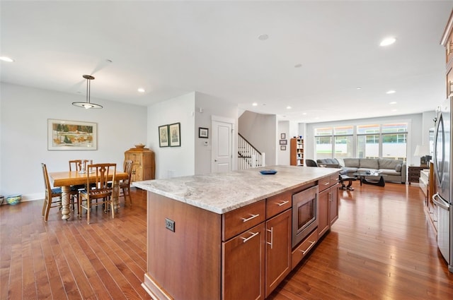 kitchen with appliances with stainless steel finishes, open floor plan, dark wood-style floors, recessed lighting, and a center island