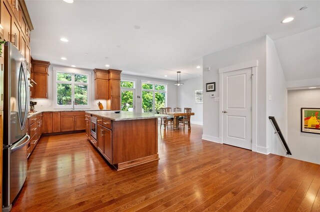 kitchen featuring freestanding refrigerator, brown cabinetry, dark wood-style flooring, plenty of natural light, and recessed lighting