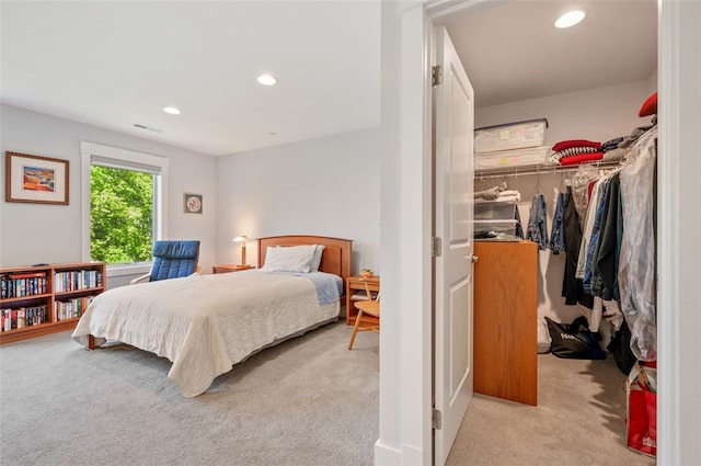 bedroom featuring light colored carpet, a walk in closet, recessed lighting, and a closet