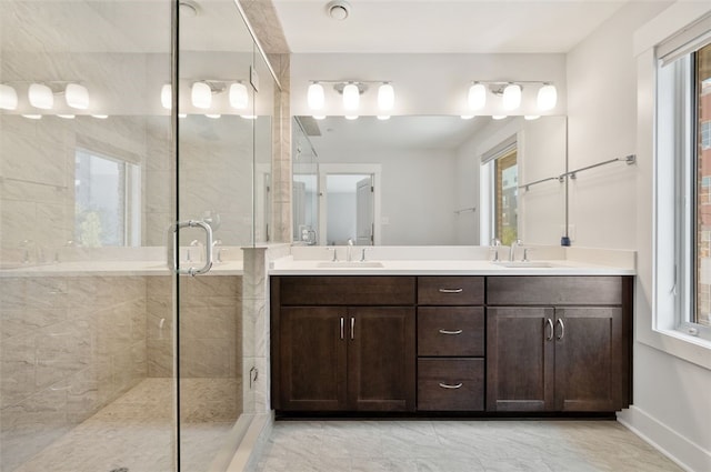 bathroom featuring a stall shower, double vanity, and baseboards
