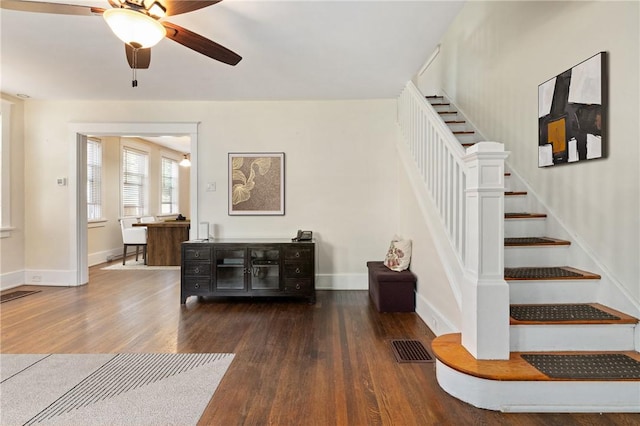 stairway with wood finished floors, a ceiling fan, and baseboards