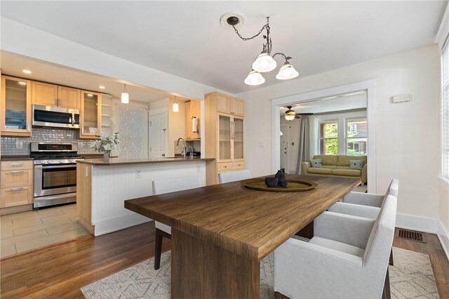dining space featuring a chandelier, light wood-style floors, a ceiling fan, and baseboards