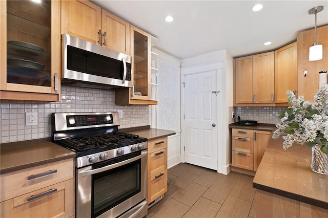 kitchen featuring stainless steel appliances, light brown cabinets, dark countertops, glass insert cabinets, and recessed lighting