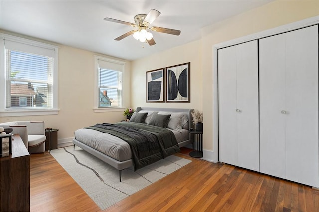 bedroom featuring wood finished floors, a closet, baseboards, and ceiling fan