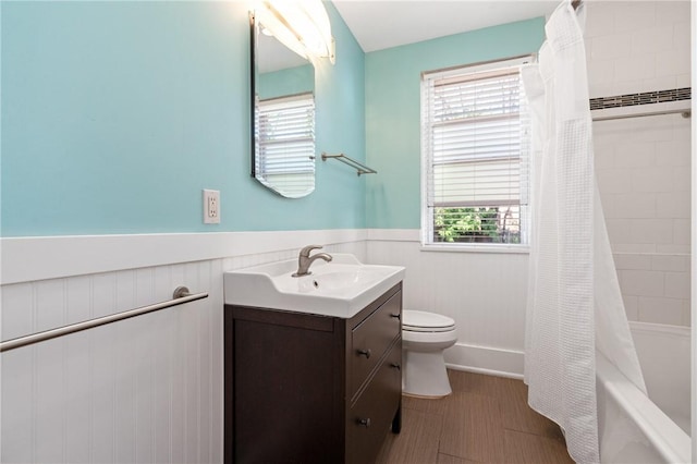 full bathroom featuring a wainscoted wall, toilet, vanity, and shower / bath combo with shower curtain