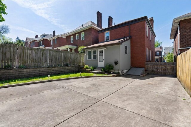 rear view of property with a fenced backyard, a patio area, stucco siding, and a chimney
