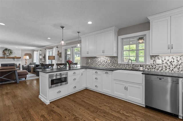 kitchen with dishwasher, dark countertops, built in microwave, a peninsula, and recessed lighting