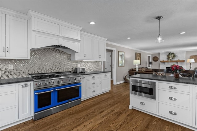 kitchen featuring appliances with stainless steel finishes, dark countertops, white cabinetry, crown molding, and recessed lighting