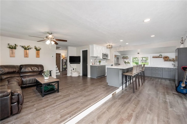 living room with a ceiling fan, wood finished floors, and recessed lighting