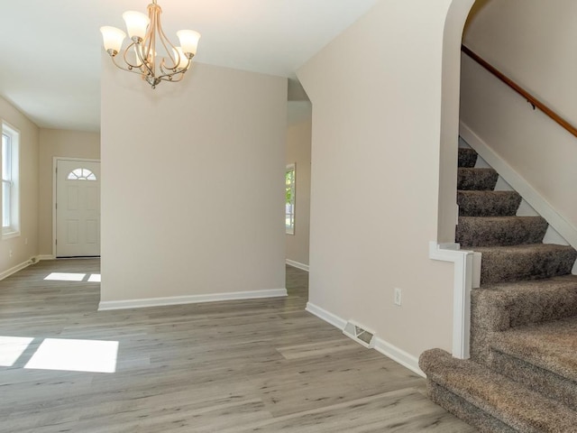 411 4th St, Darlington, PA 16115 - unfurnished dining area featuring stairs, light wood-style flooring, baseboards, arched walkways, and a chandelier